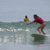 A woman surfing in a red shirt