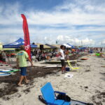 A photograph up the beach of tents and spectators