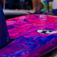 A photo of the underside of a surfboard with a blue pink and purple marbalized pattern