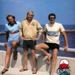 ( L R ) DICK CATRI, JEFF CRAWFRD AND MIKE TABELING ATOP THE SEBASTIAN INLET BRIDGE POSING FOR A CALIFORNIA T SHIRTS AD FEATURED IN THE 1978 ISSUE OF "SURF MAGAZINE". COURTESY SURF MAGAZINE